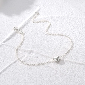 Detailed close-up of a minimalist 925 sterling silver chain bracelet with a heart pendant