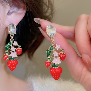 Detail of vintage strawberry earrings with red enamel and zircon on a gold-plated setting