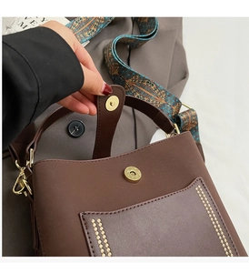 Close-up of vintage brown PU leather bag featuring a patterned ethnic wide strap and metal clasp