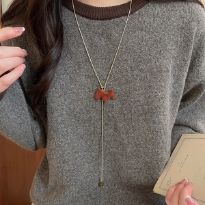 Detailed macro of golden Y-shaped necklace with a brown flocked Scottie dog pendant