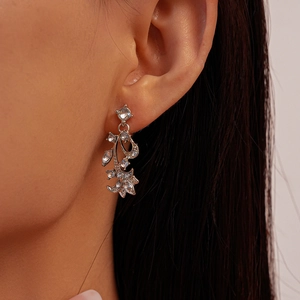 Close-up of elegant leaf-shaped drop earrings with sparkling crystals on a model