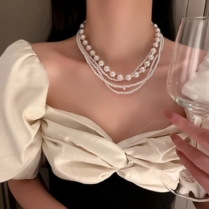 Close-up of triple-layer white pearl necklace with gold beads on elegant model