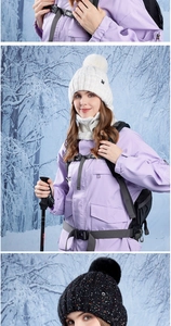 Detailed view of light purple winter jacket paired with white knit beanie and scarf in snow