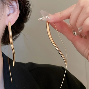 Detailed view of long gold drop earrings with minimalist double asymmetrical curves