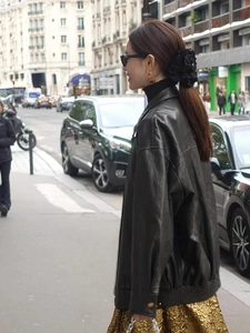 Detail of a large black lace flower hair claw clip worn by a model in a stylish street setting