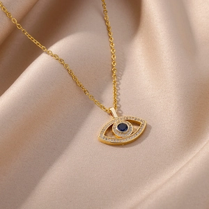Detail of gold evil eye necklace with blue zircon inlay on smooth satin background