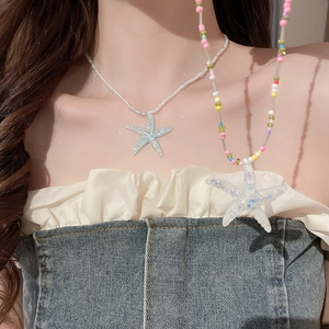 Detail of colorful beaded necklaces with iridescent starfish pendants on model