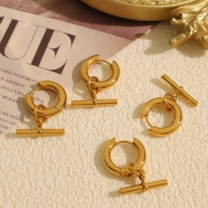 Élégantes boucles d'oreilles dorées avec fermoir OT sur fond de marbre chic