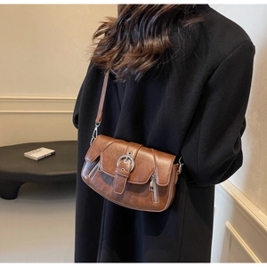 Close-up of brown vintage saddle bag with metal buckle and double zipper details
