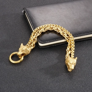 Detailed close-up of golden dual wolf head clasp and heavy braided chain on a male bracelet