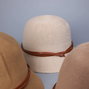 Close-up of knitted bucket hat with brown leather straps and metallic rivets details