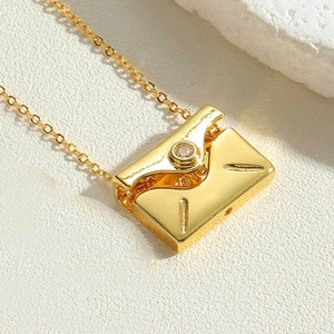 Detailed macro view of gold envelope pendant with LOVE engraving and clear zircon stone