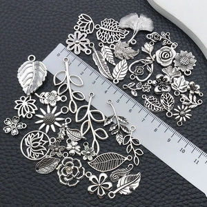 Vue détaillée de breloques feuilles et fleurs en argent à côté d'une règle graduée