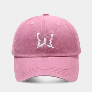 Close-up of intricate white butterfly embroidery on a pink washed cotton baseball cap