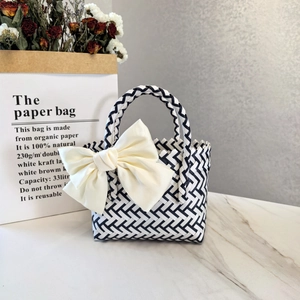 Macro detail of hand-woven geometric bag with a decorative oversized creamy white bow