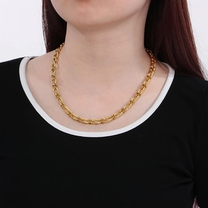 Detail of a shiny gold-plated 3:1 pattern curb chain necklace worn by a model