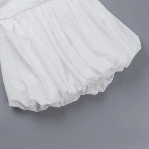 Gros plan détaillé de l'ourlet bouffant blanc et des coutures texturées sur la robe