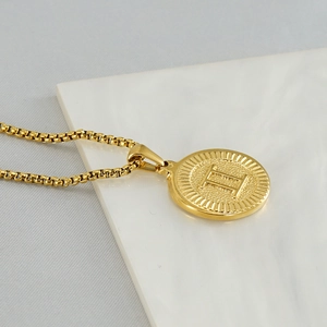Detailed macro shot of 18k gold plated Gemini constellation coin pendant and square chain