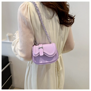 Detail view of mini lavender leather saddle bag with woven chain strap on a model