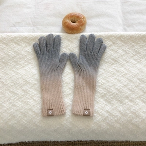 Detailed close-up of grey and beige gradient knitted gloves with ribbed texture and logo