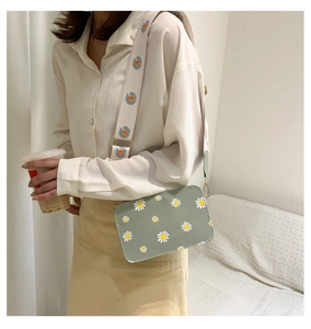 Detail of green crossbody bag with daisy prints and floral embroidered strap