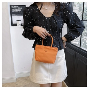Sac seau chic en nylon orange avec logo, porté par un mannequin dans un cadre intérieur élégant