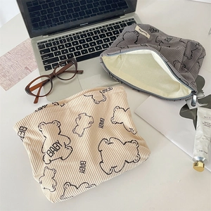 Detail of bear print corduroy pouches with zipper and lining in a lifestyle desktop setting