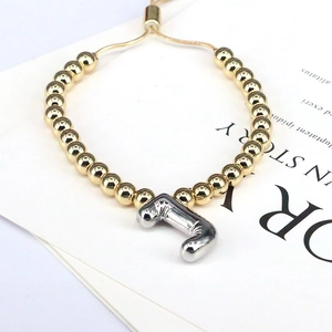 Detail of adjustable gold beaded bracelet featuring a silver balloon letter J charm