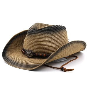 Detail of western straw hat featuring a metal bull head emblem and beaded strap