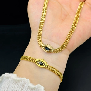 Detail showing gold wheat chain necklace with blue evil eye pendant on model neck