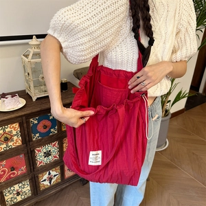 Detail of red striped tote bag with drawstring closure and white logo patch