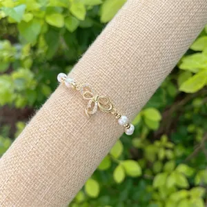 Detailed macro of crystal bow on pearl bracelet with 18K gold plated brass elements