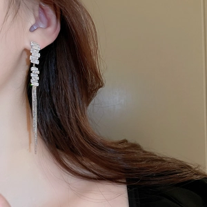Macro detail of long silver chain tassel earrings with sparkling zircon gemstones