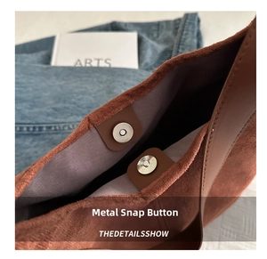 Detail view of the metal magnetic clasp closure and premium suede texture on a tote bag