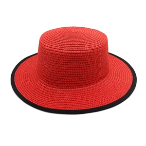 Detailed texture of red straw boater hat with black binding and woven precision finish