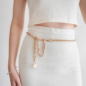 Detail of gold chain belt with punk style hollow links and a sun charm pendant