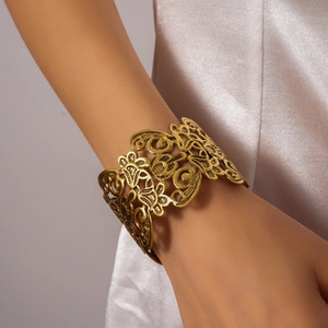 Close-up detail of vintage gold hollow carved cuff bracelet with ethnic floral pattern