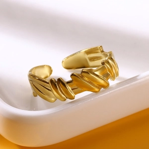 Detailed view of a gold-plated irregular geometric stainless steel open ring on a ceramic plate
