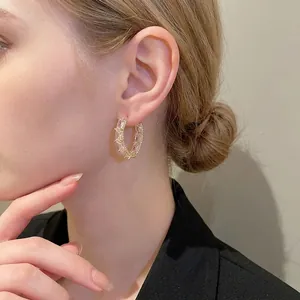 Elegant gold-tone C-shape hoop earrings with baguette-cut zircons worn by a model