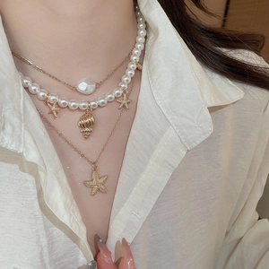 Close-up of layered necklace with white pearls, gold starfish and shell pendants