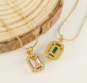 Detail of square zircon necklaces with pink and green stones on gold plated S-chain