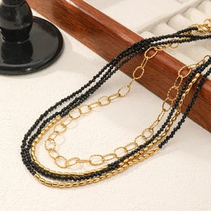 Three-layer black spinel beaded necklace with gold titanium steel chains on wood