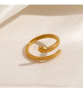 Macro detail of gold snake ring with textured scales on soft white silk background