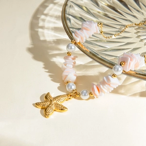 Detail of 18k gold necklace featuring a pink shell petal and small pearl pendant