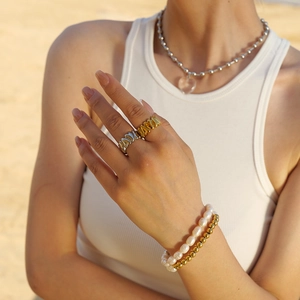 Gold and silver stainless steel jewelry set with heart necklace on a beach background