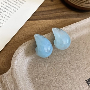 Detail view of light blue resin teardrop earrings with marble texture on vintage background