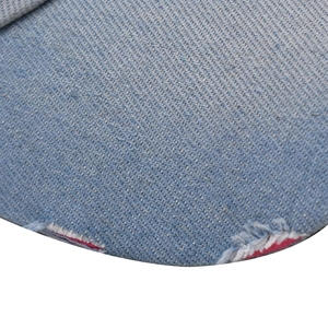 Dettaglio ravvicinato del tessuto denim lavato azzurro con effetti di bordi sfrangiati