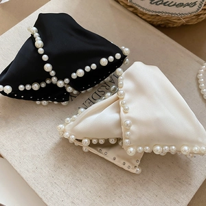 Détail de pinces à cheveux en satin avec bordure en perles et rivets dorés