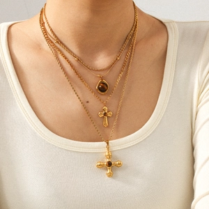 Layered gold titanium necklace featuring tiger eye stone and cross pendants on model