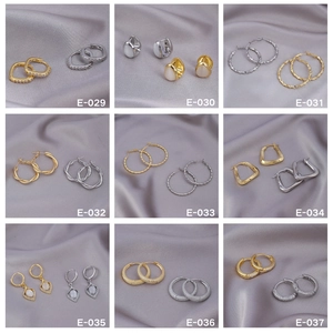 Collection of nine gold and silver hoop earrings with cat eye stones on grey silk fabric